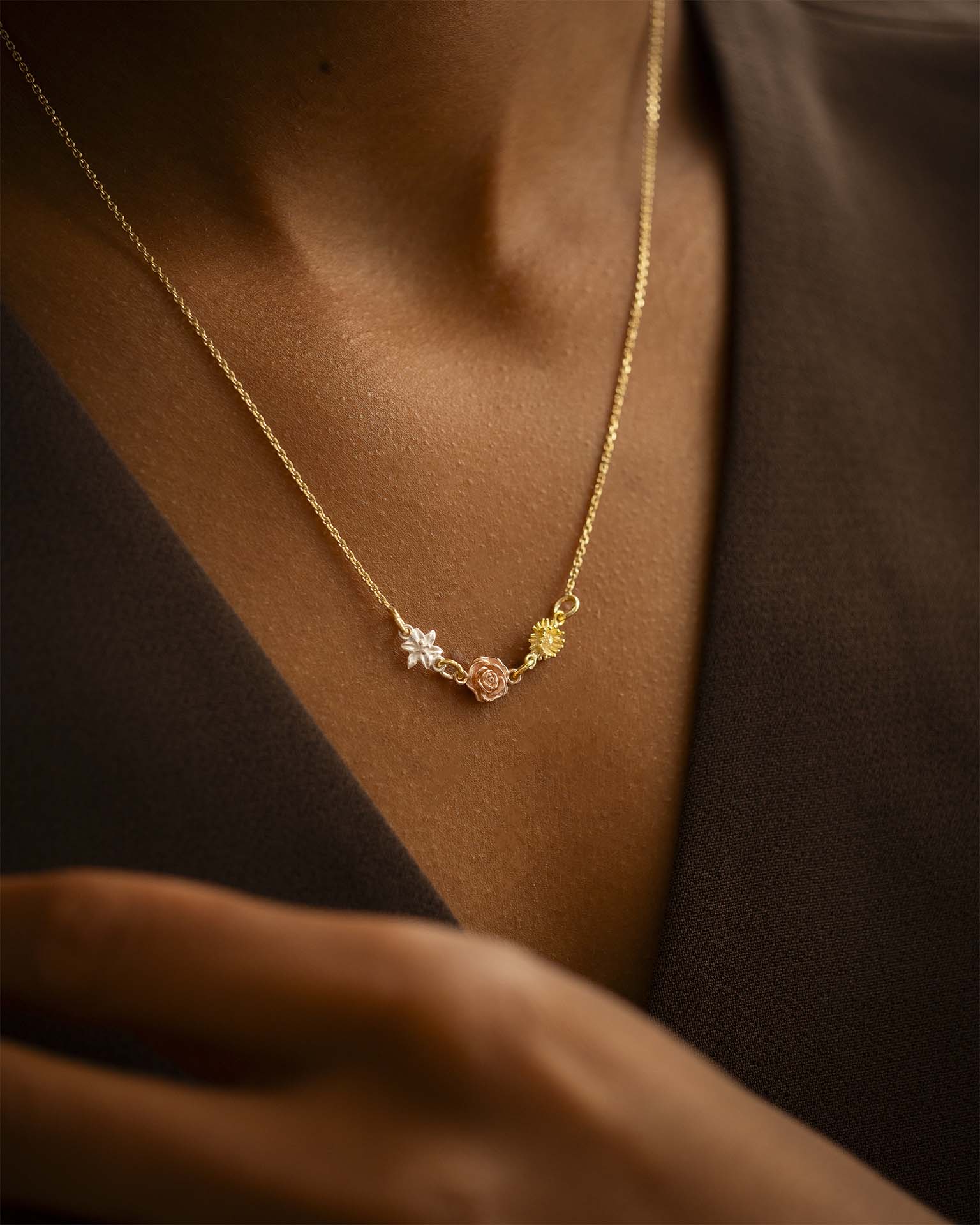 Gold necklace with star and rose pendant on a person wearing a brown garment. | Christmas