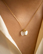 Gold necklace with heart-shaped pendants on a person wearing a white garment.
