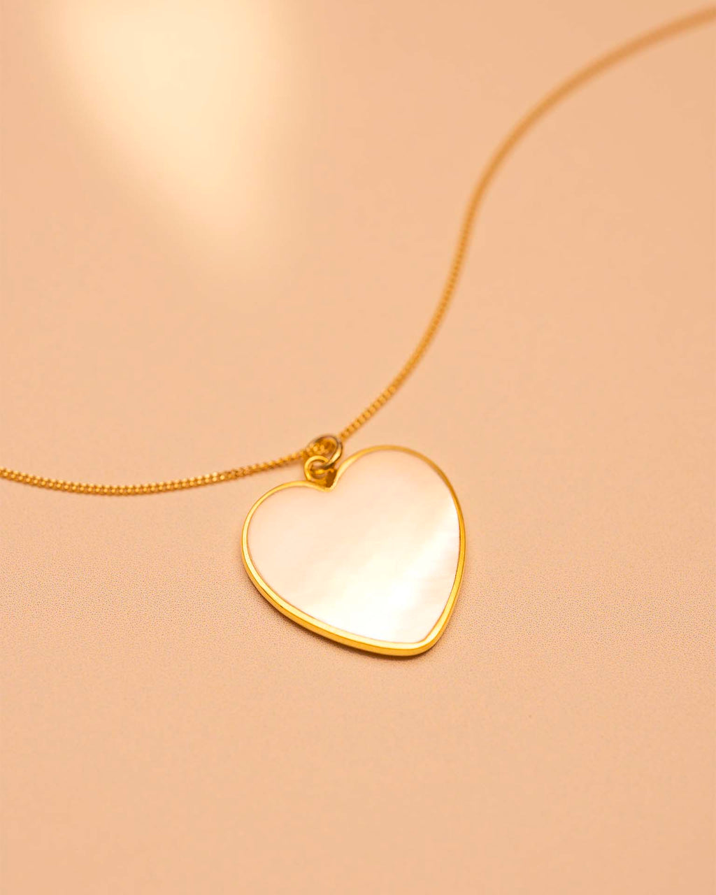 Heart-shaped pendant necklace on a beige background