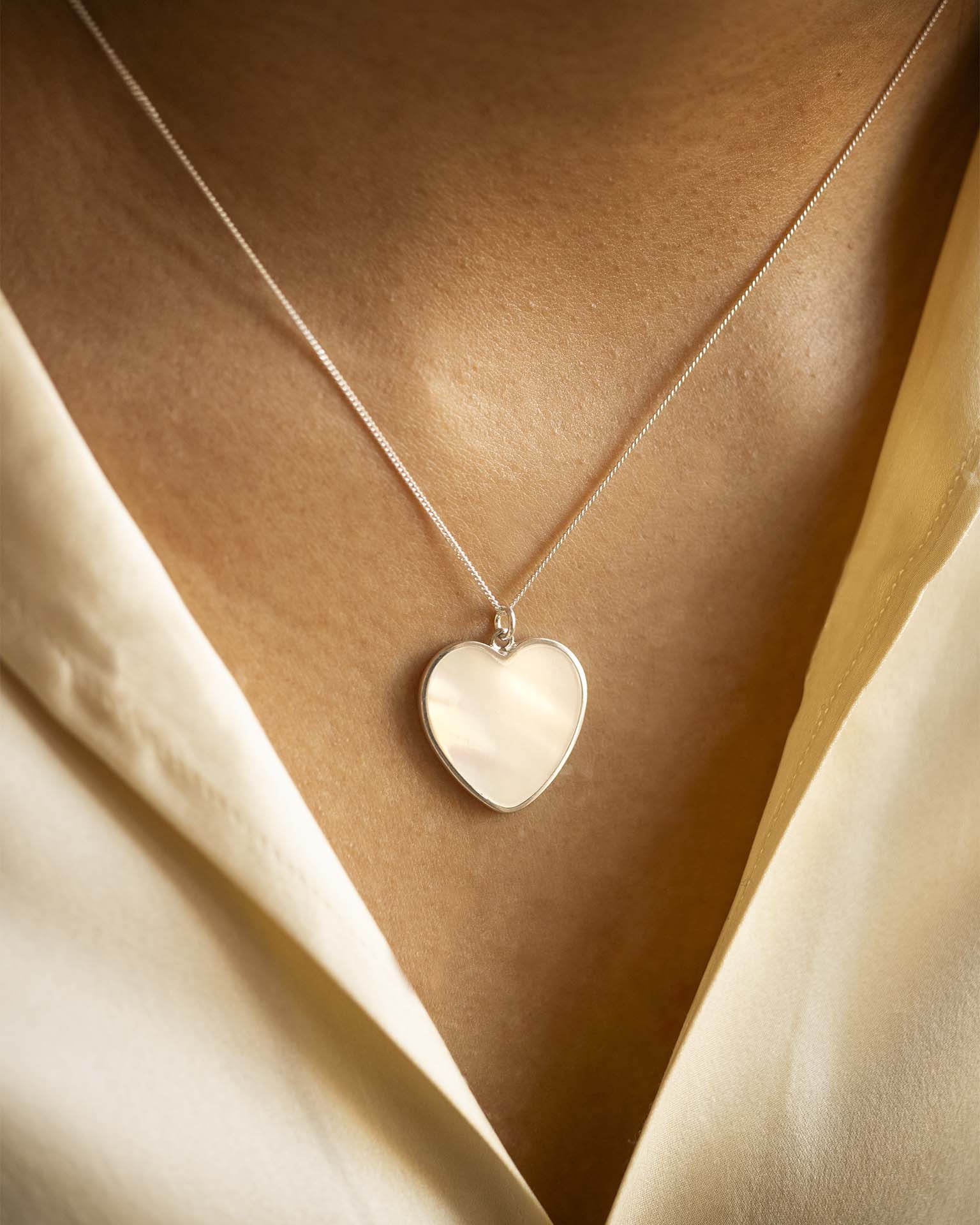 Heart-shaped pendant necklace on a beige fabric background