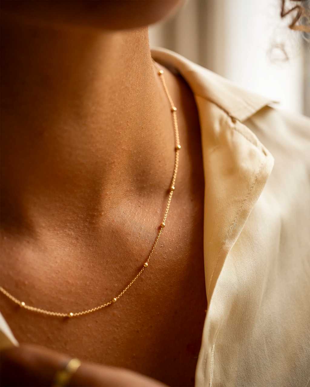 Close-up of a person wearing a gold necklace with a neutral background | Christmas