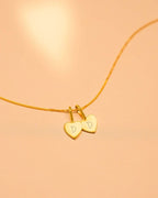 Gold necklace with heart-shaped charms on a peach background