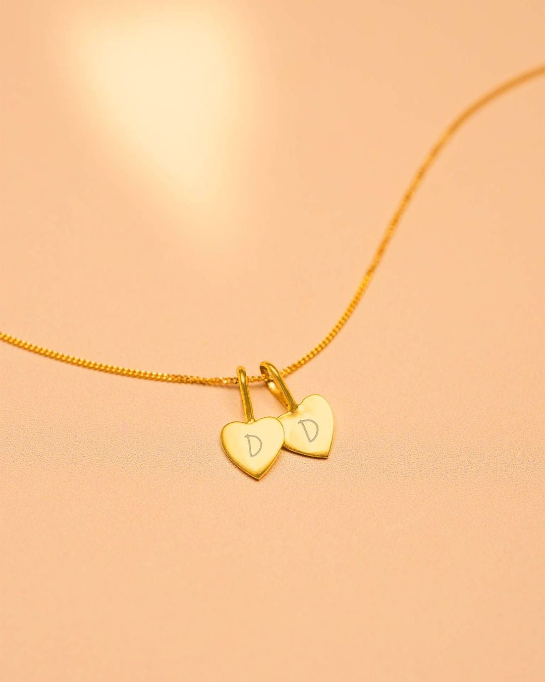 Gold necklace with heart-shaped charms on a peach background