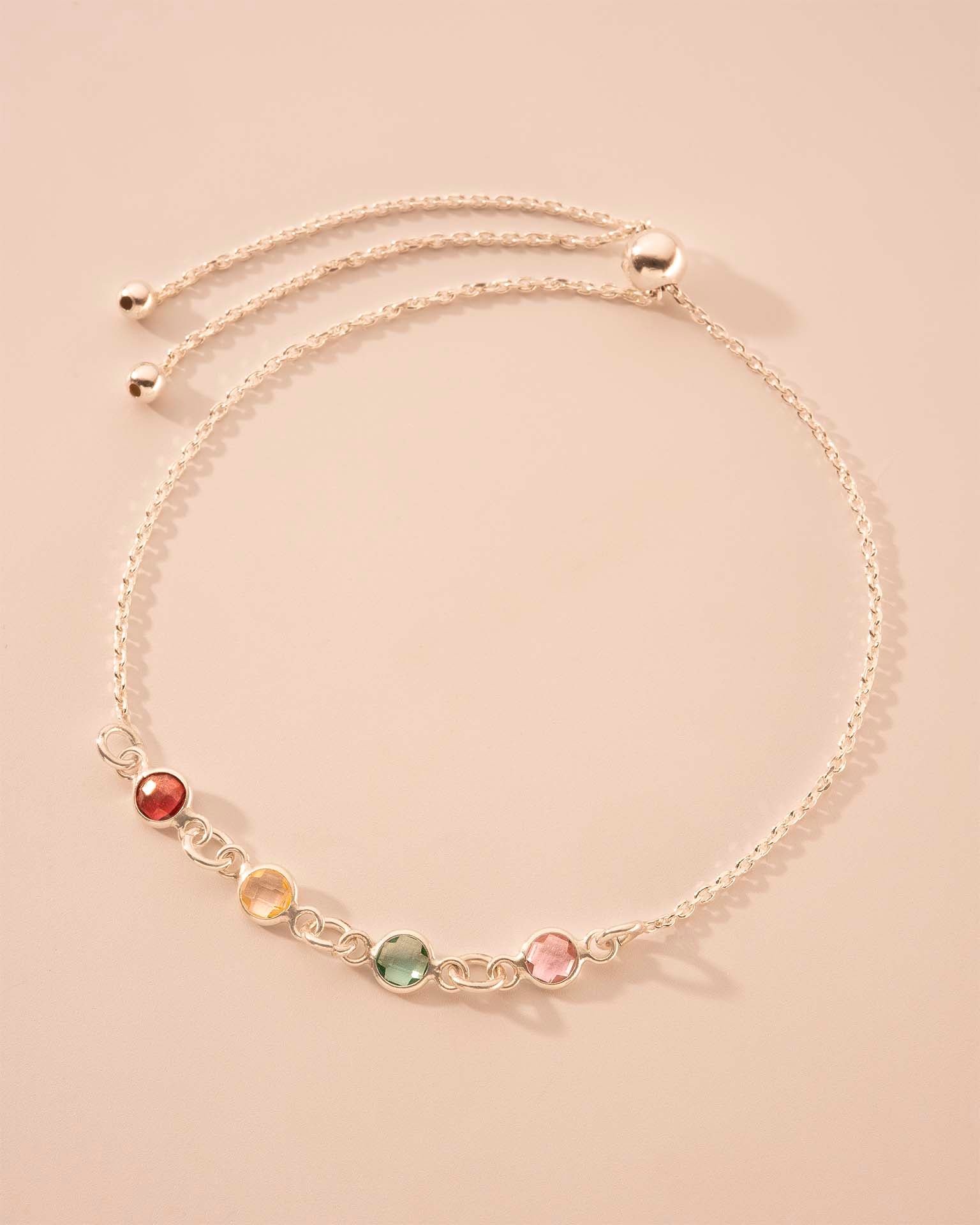 Delicate gold necklace with multicolored beads on a beige background