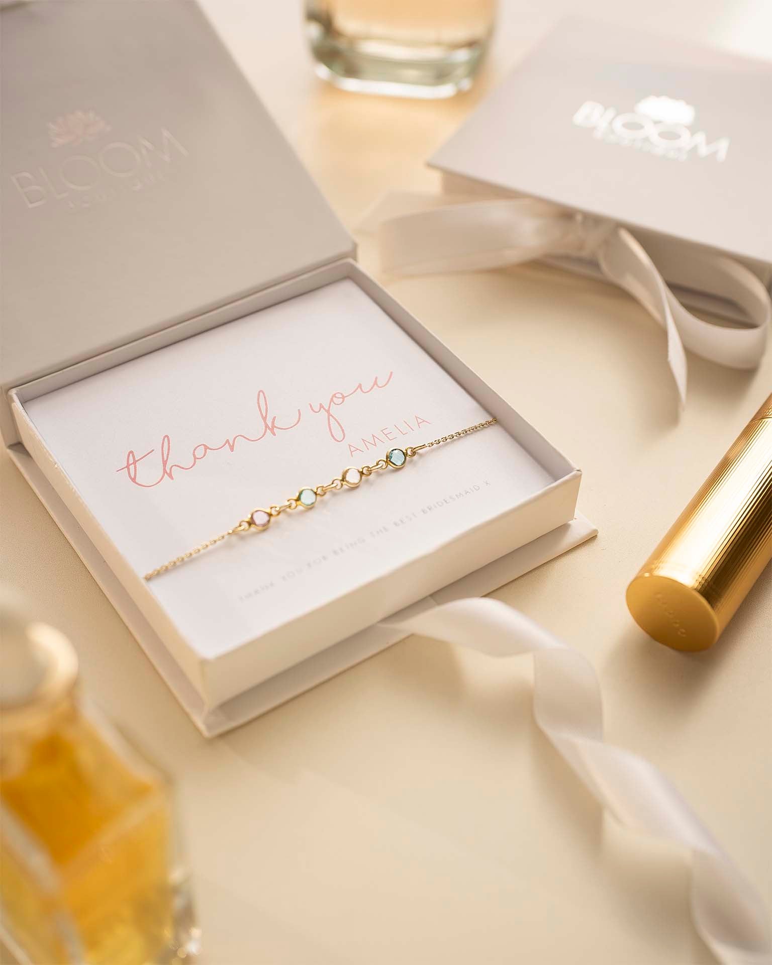 Gold bracelet in a box with 'thank you' message on a light background