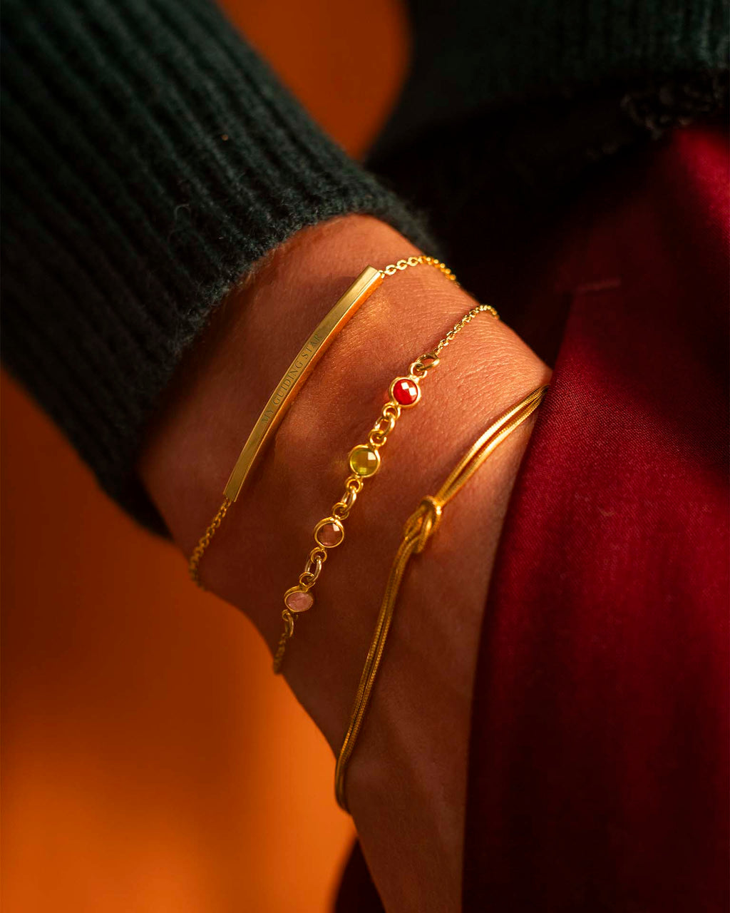 Gold bracelets with gemstones on a wrist against a blurred background