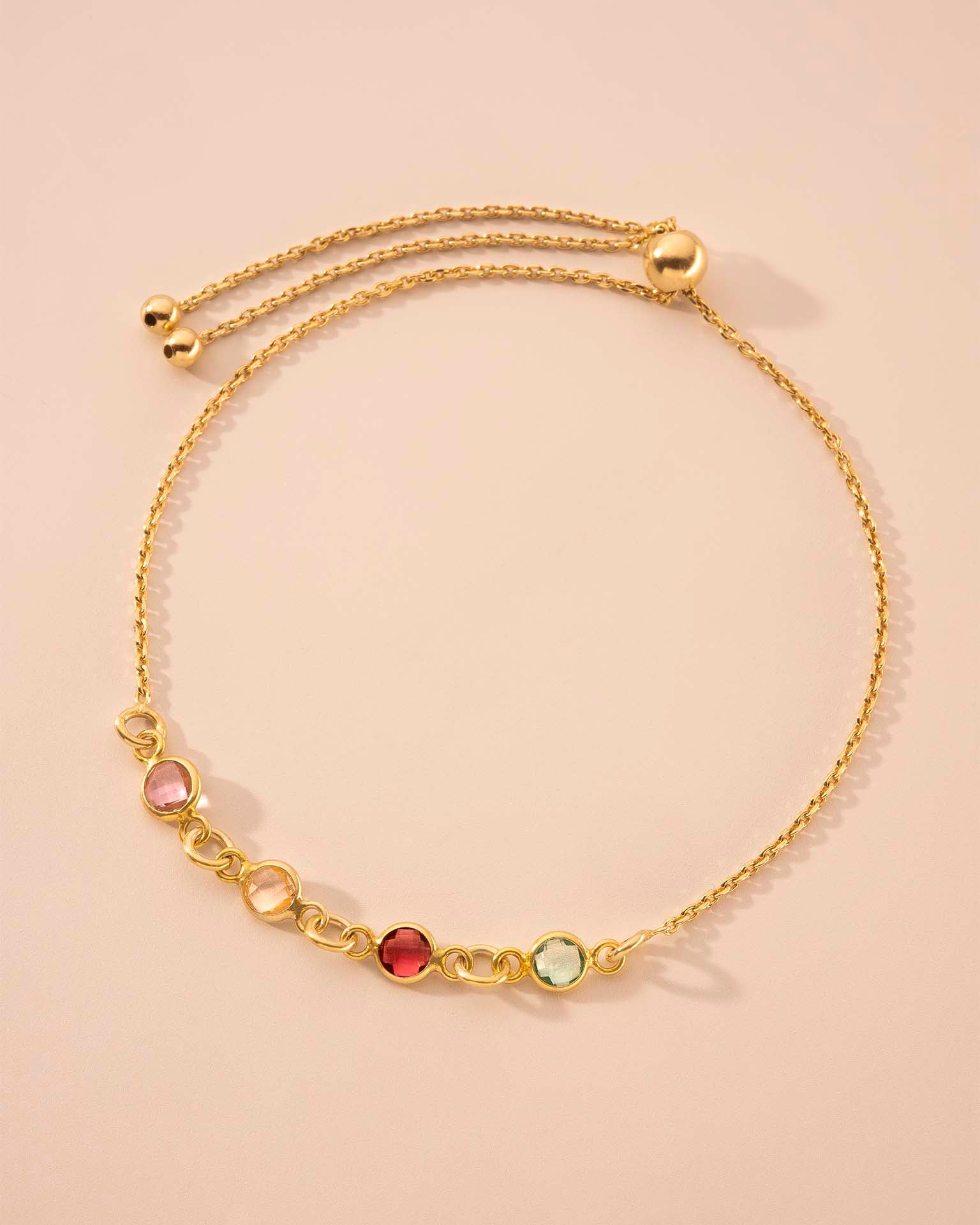 Gold bracelet with colorful beads on a beige background