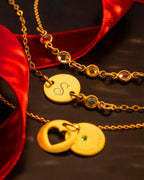 Gold necklaces with engraved designs on a dark surface with red fabric