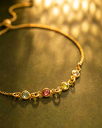 Gold bracelet with embedded gemstones on a dark surface | Christmas