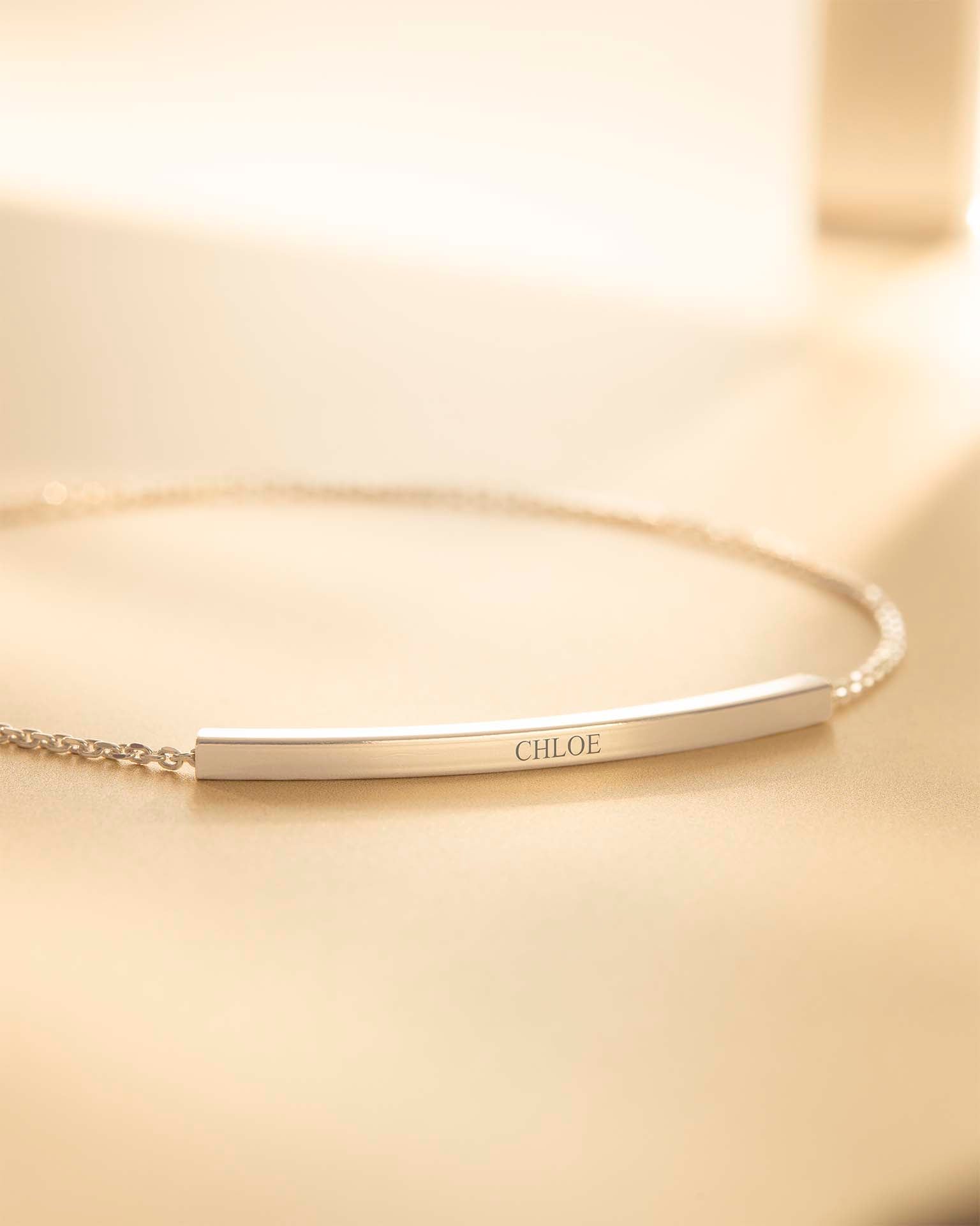 Gold bracelet with 'CHLOE' engraving on a beige background