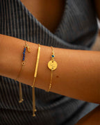 Close-up of a wrist wearing multiple gold bracelets with various designs.
