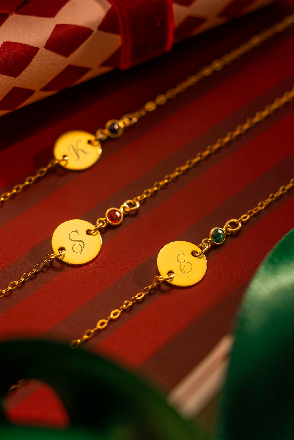Gold necklaces with engraved pendants on a red striped background