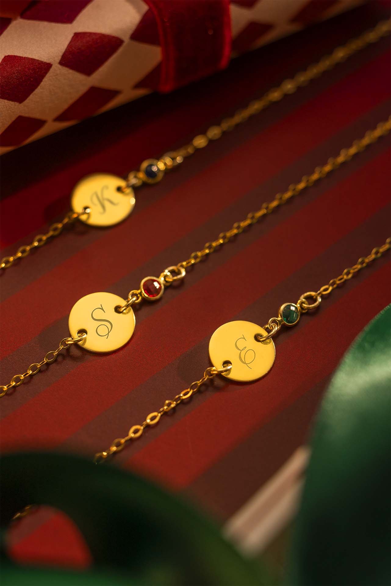 Gold necklaces with engraved pendants on a red striped background