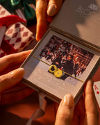 Person holding a jewelry box with a heart-shaped pendant, surrounded by festive decorations.