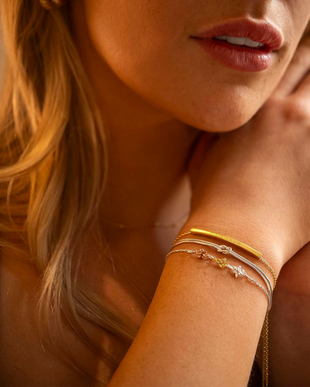 Close-up of a woman's arm with gold bracelets, focusing on jewelry.
