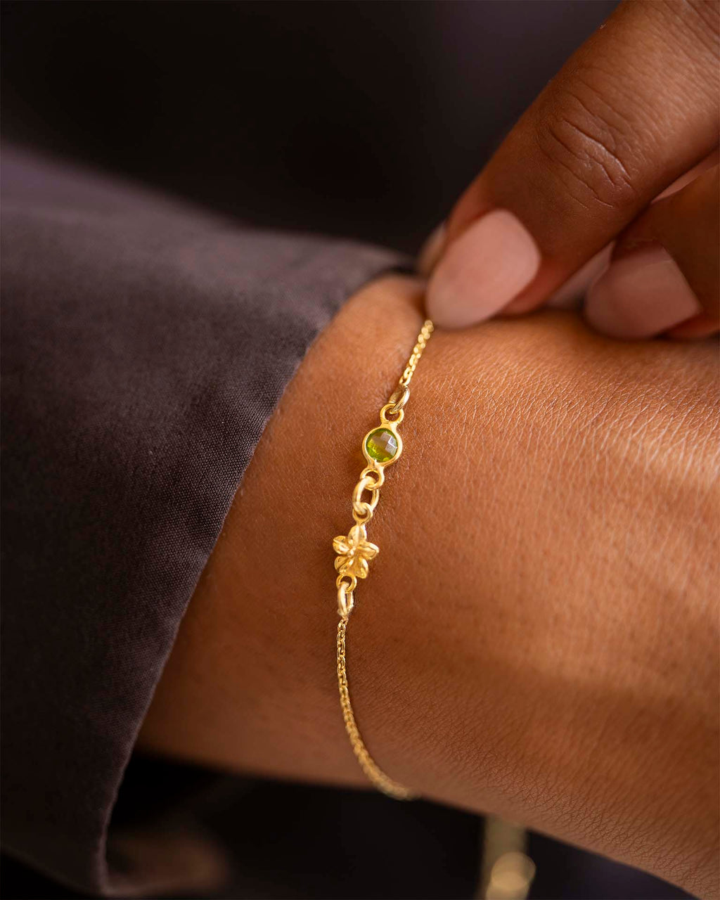 Gold bracelet with a green gemstone on a wrist against a dark background | Christmas