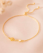 Gold bracelet with a sunflower charm on a beige background