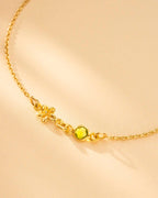 Gold necklace with a green gemstone on a beige background