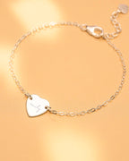 Silver bracelet with a heart-shaped tag on a gold background