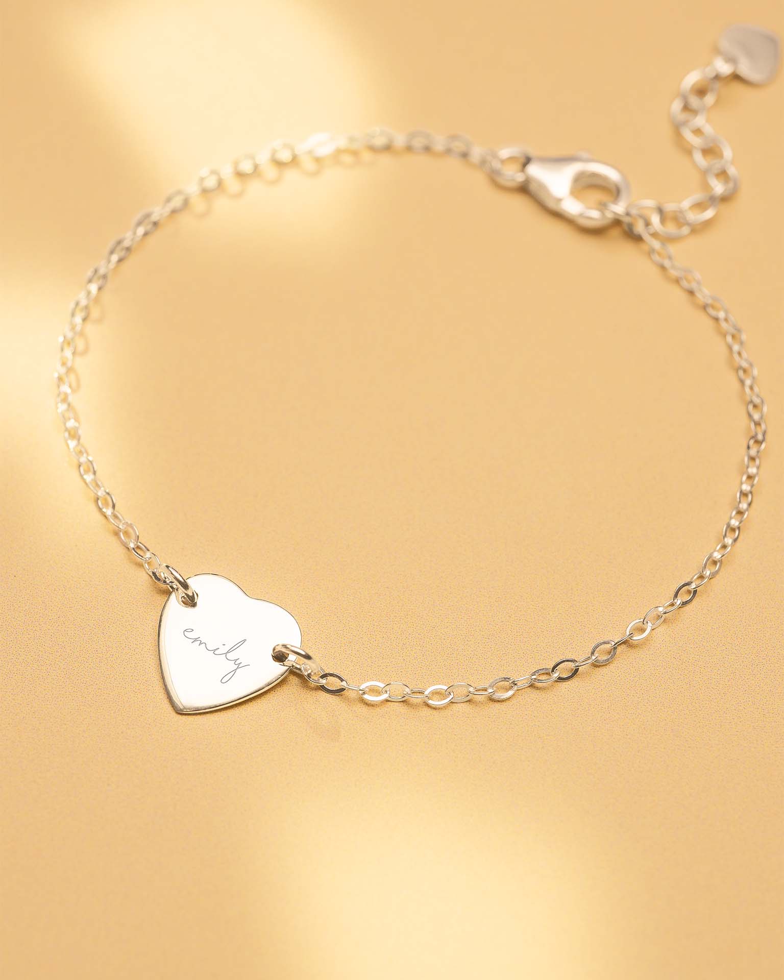 Silver bracelet with a heart-shaped tag on a gold background