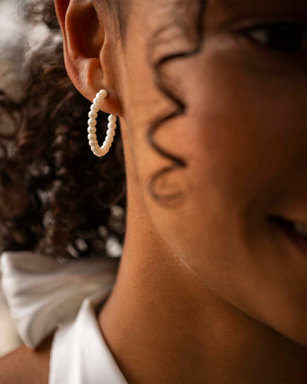 Close-up of a person wearing a pearl hoop earring. | Christmas 