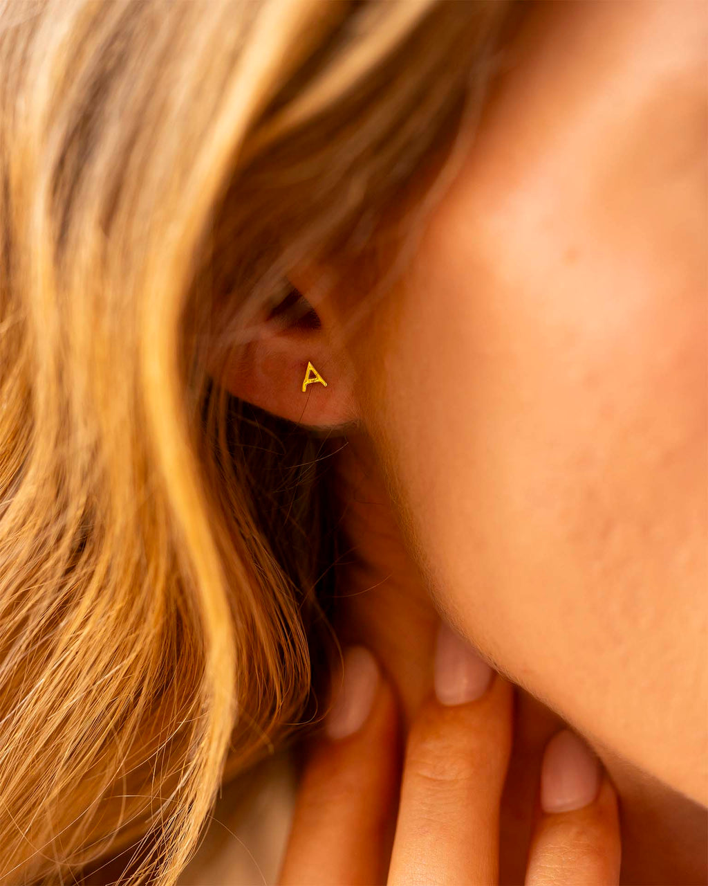 Close-up of a person wearing a gold triangle earring. | Christmas
