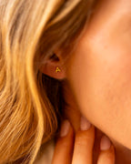 Close-up of a person wearing a gold triangle earring. | Christmas