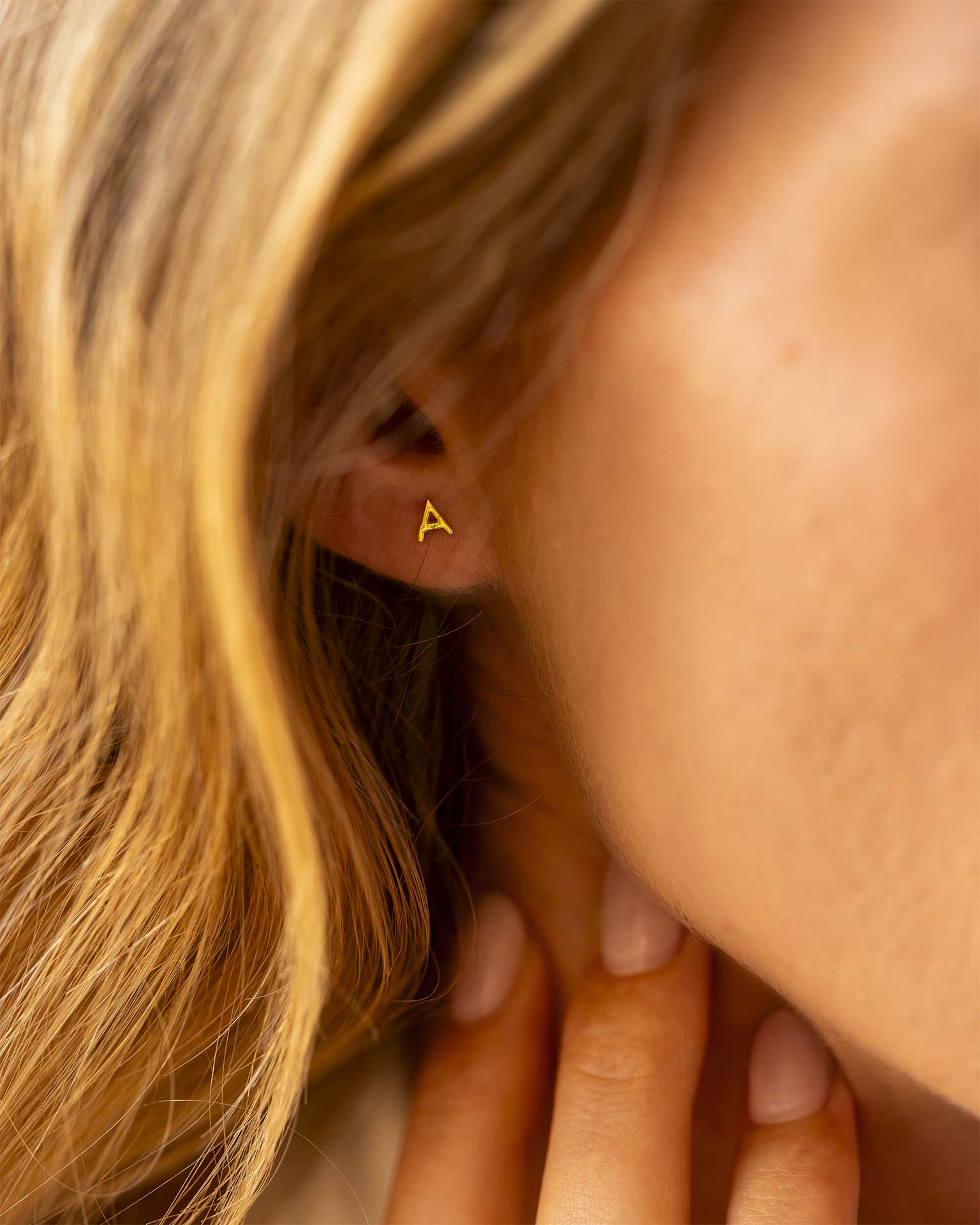 Close-up of a person wearing a gold triangle earring. | Christmas