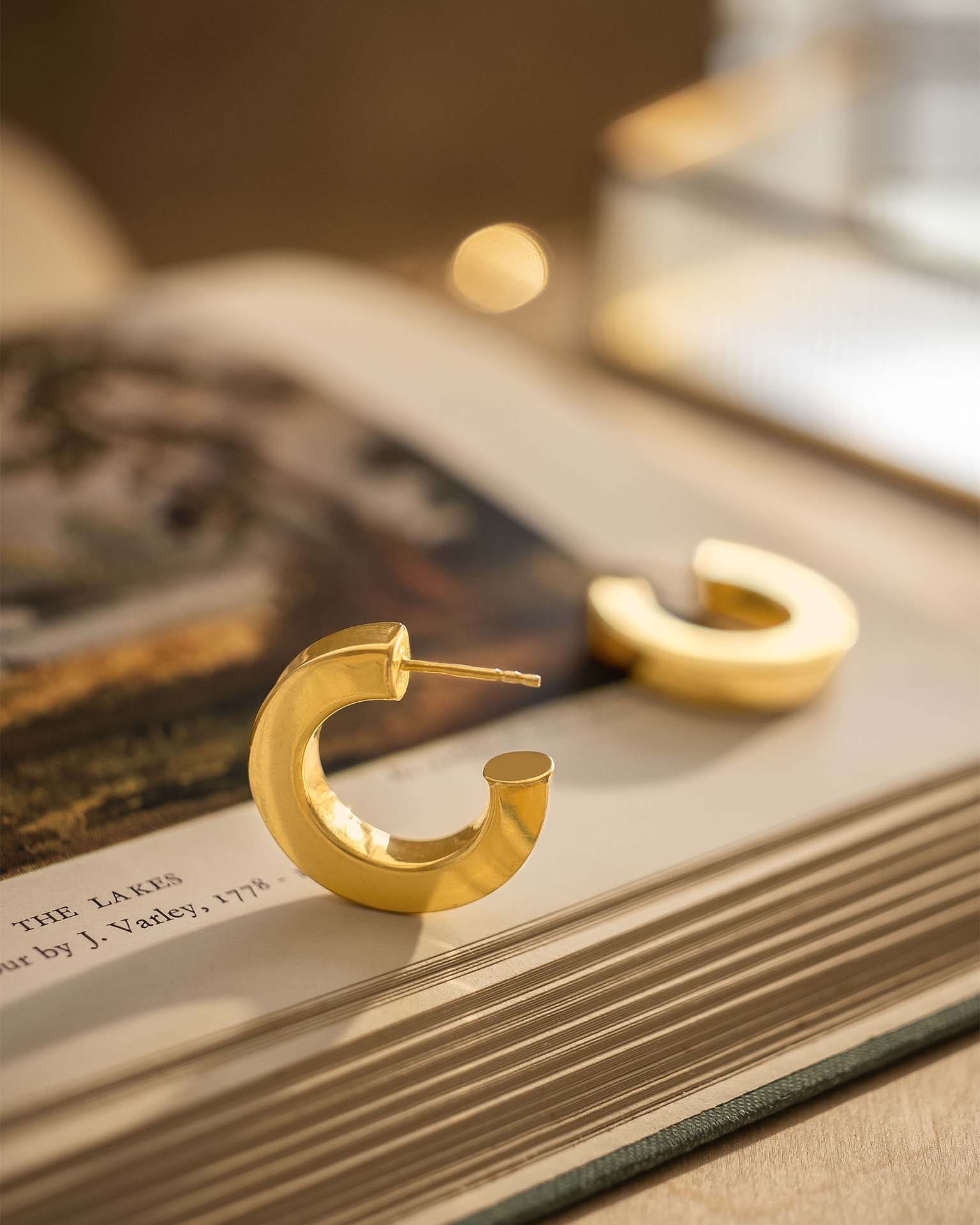 Gold hoop earrings on a book