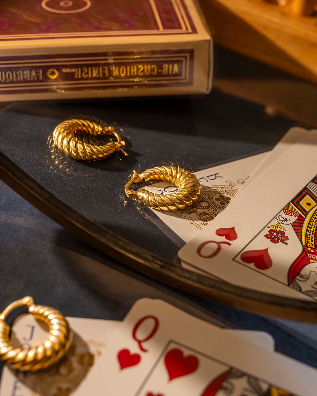Gold hoop earrings on playing cards with a deck of cards in the background