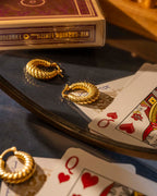 Gold hoop earrings on playing cards with a deck of cards in the background