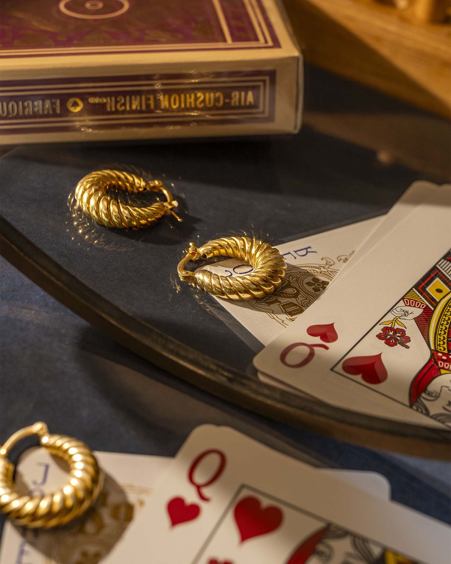 Gold hoop earrings on playing cards with a deck of cards in the background
