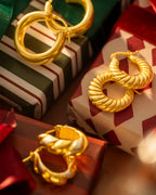 Gold hoop earrings on top of wrapped presents with a warm glow