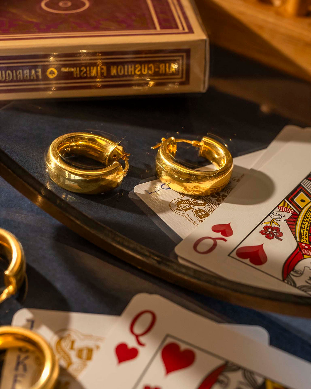 Gold hoop earrings on playing cards with a deck of cards in the background