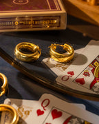 Gold hoop earrings on playing cards with a deck of cards in the background