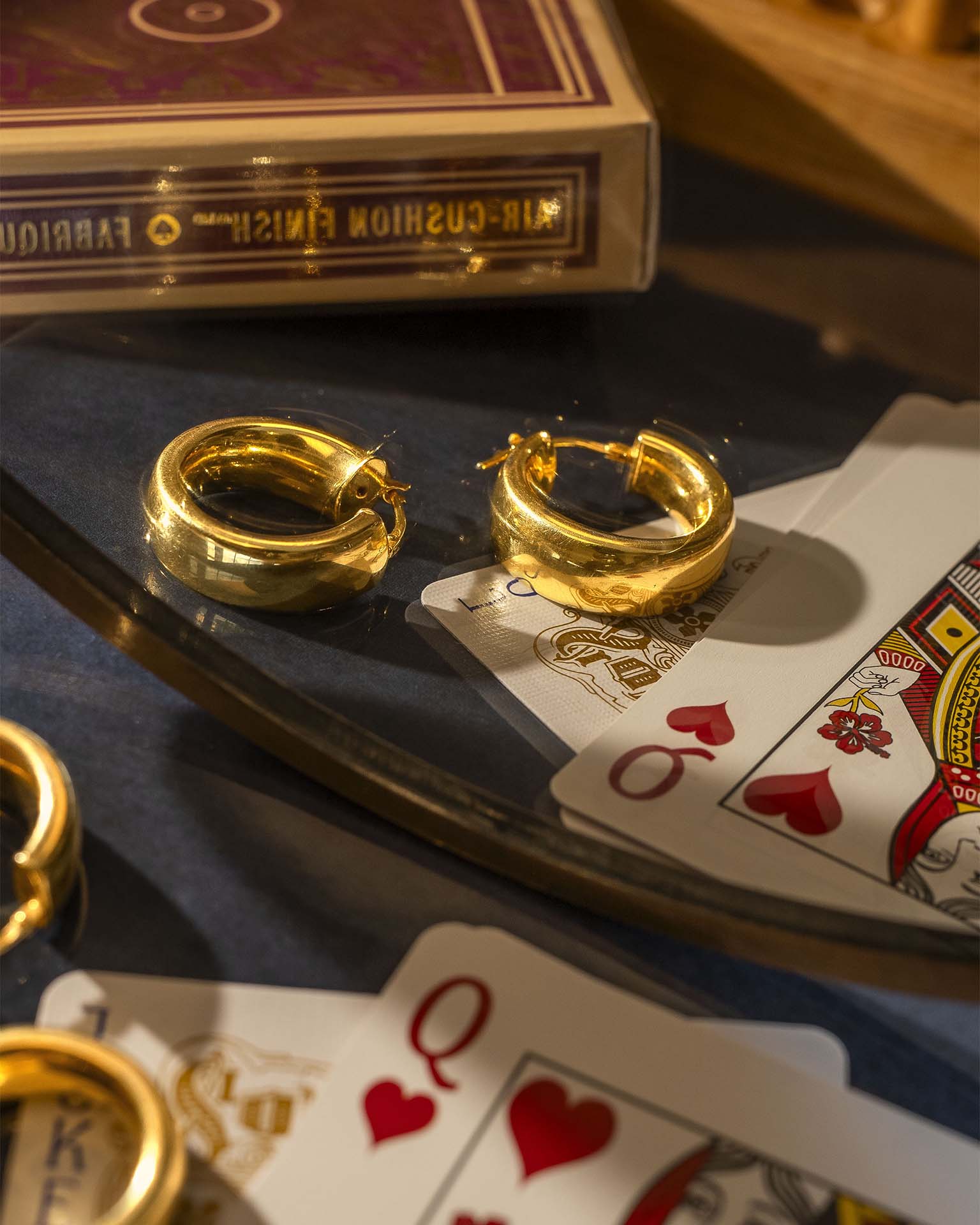 Gold hoop earrings on playing cards with a deck of cards in the background