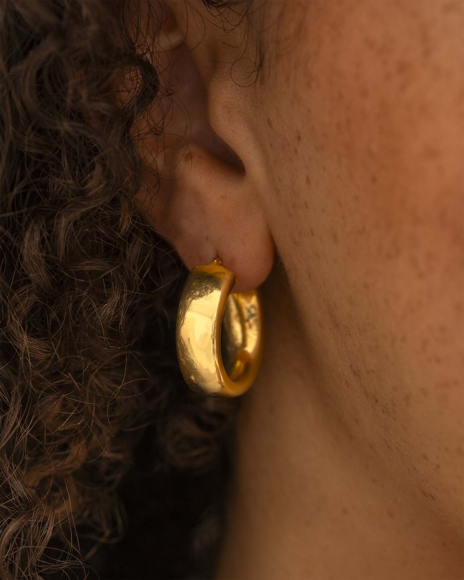 Close-up of a person wearing a gold hoop earring. | Christmas
