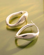Pair of silver hoop earrings on a reflective surface