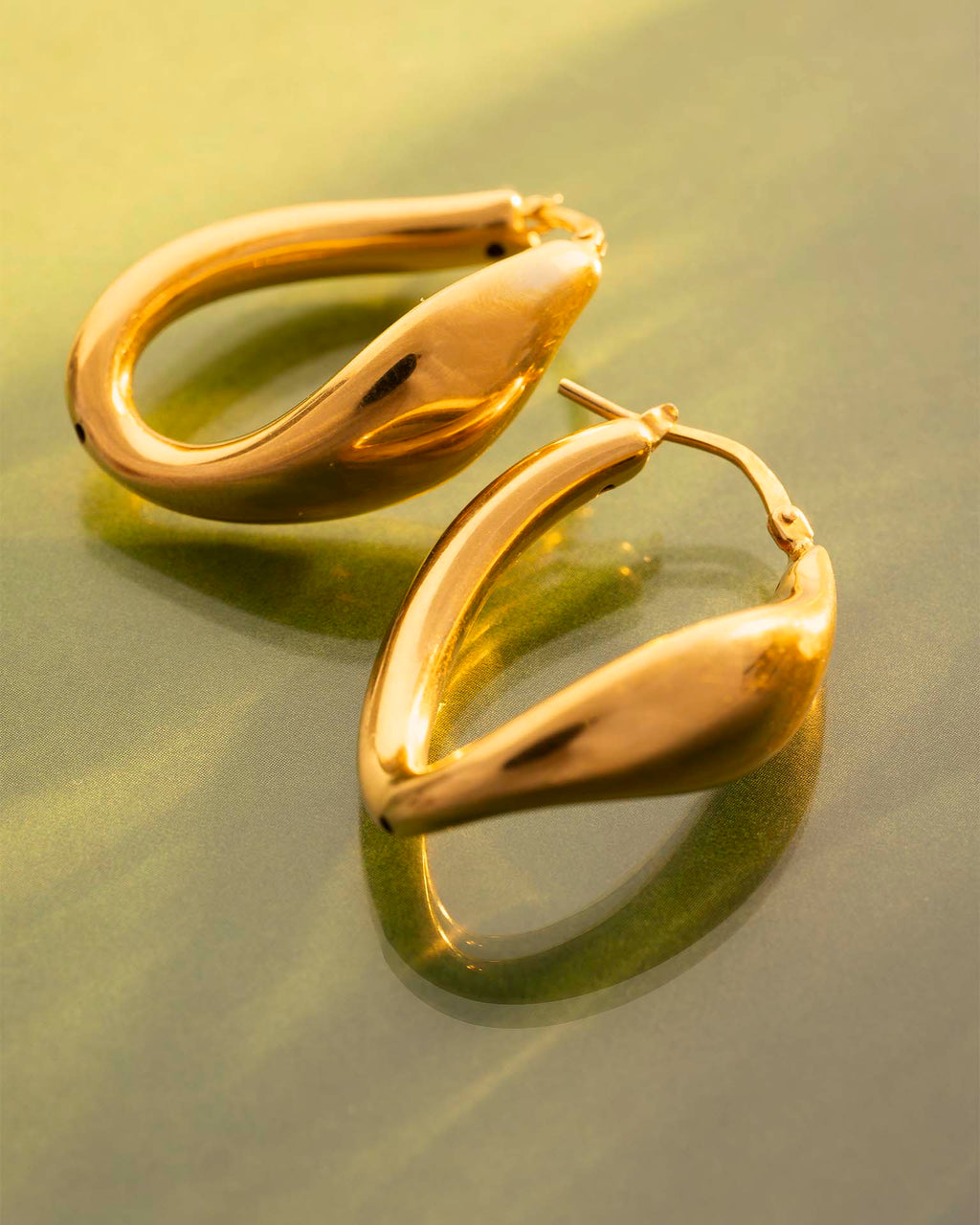 Gold hoop earrings on a reflective gold surface | Christmas
