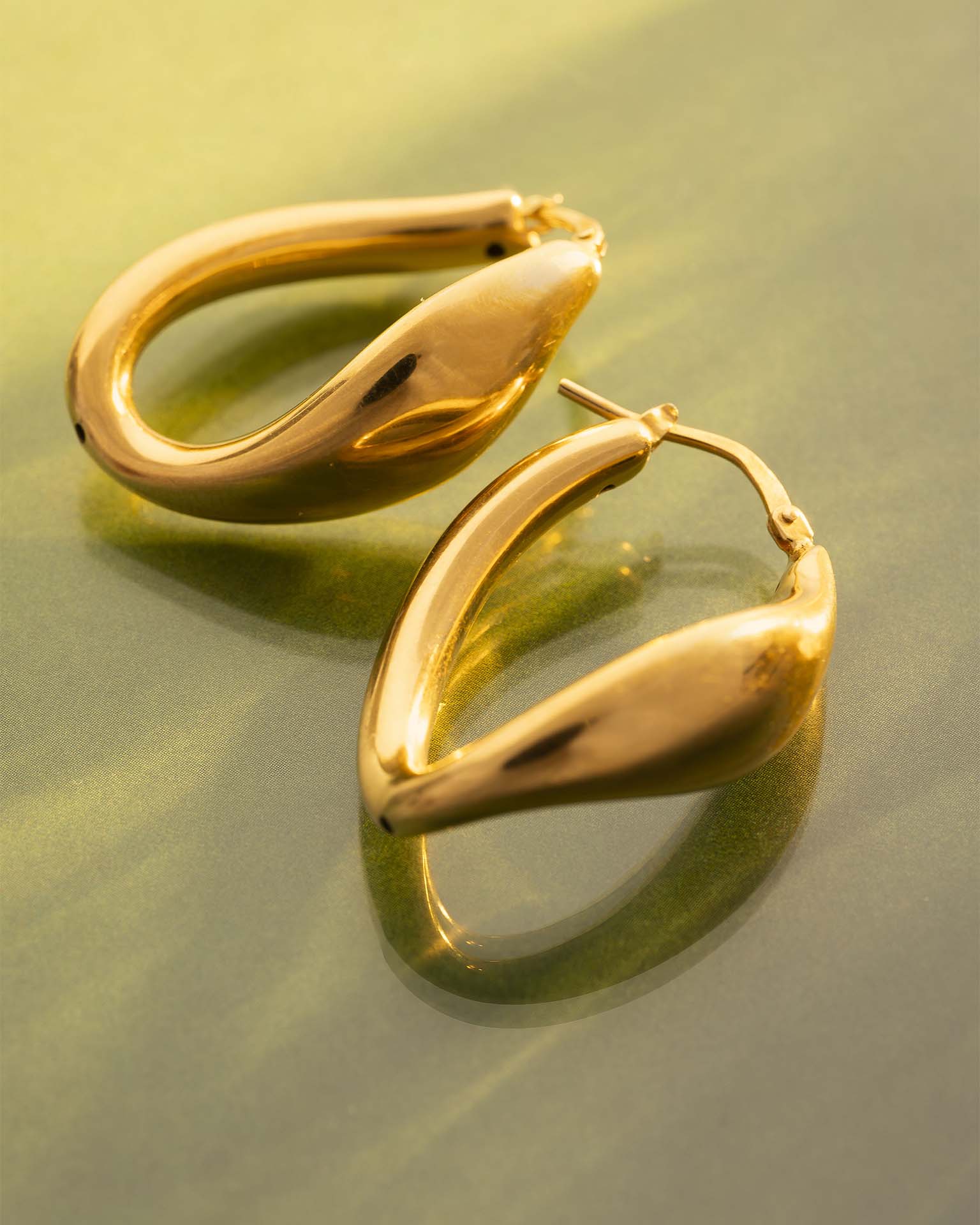 Gold hoop earrings on a reflective gold surface | Christmas