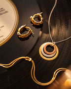 Gold jewelry including earrings and a necklace on a vinyl record