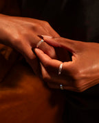 Close-up of two hands with silver rings on a dark background