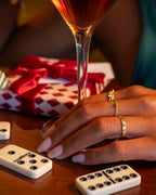 Close-up of a hand holding a glass of red wine with dominoes and a gift box in the background