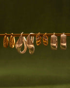 Set of gold and rose gold hoop earrings on a dark green background