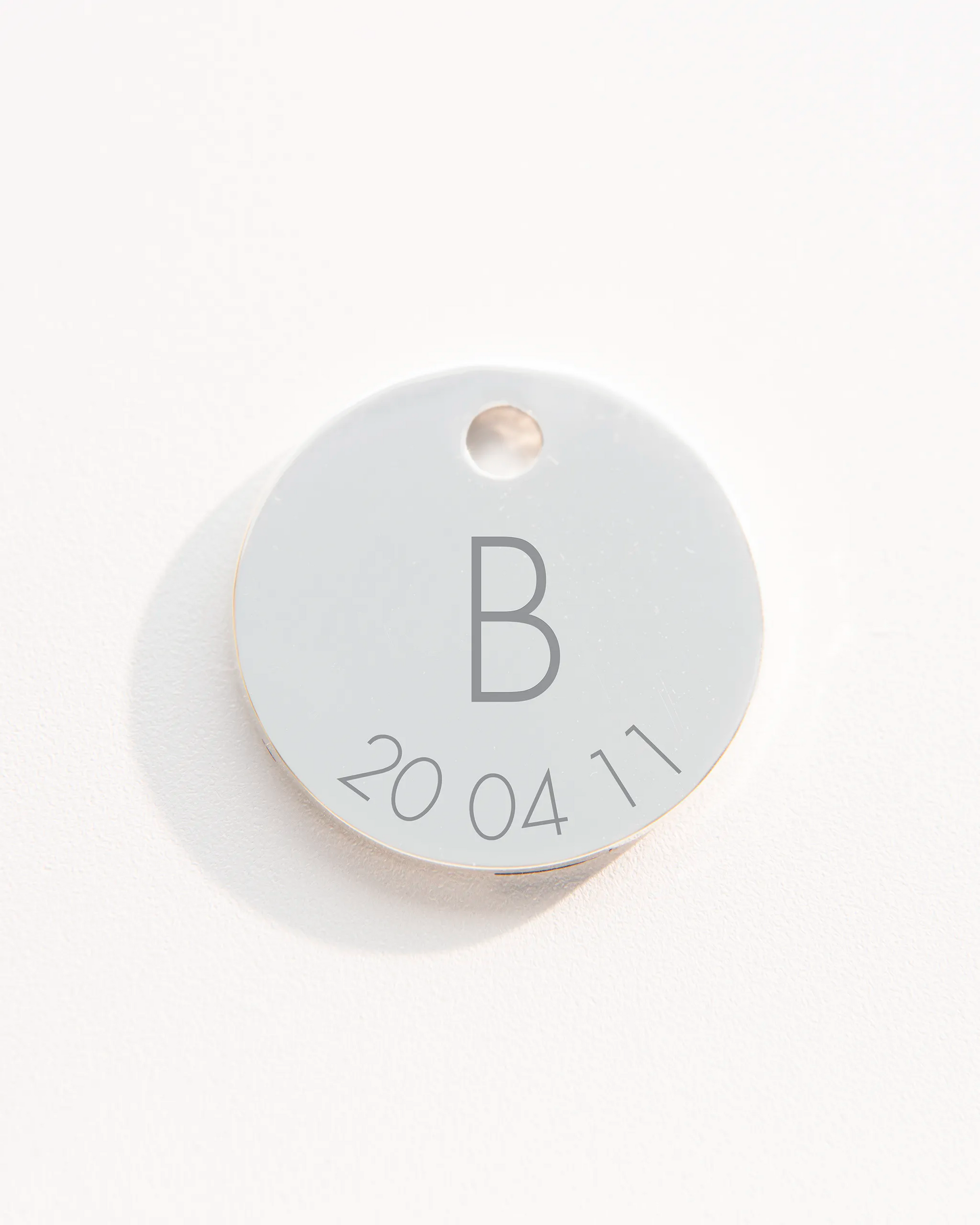 Silver disc charm with initial and date 
