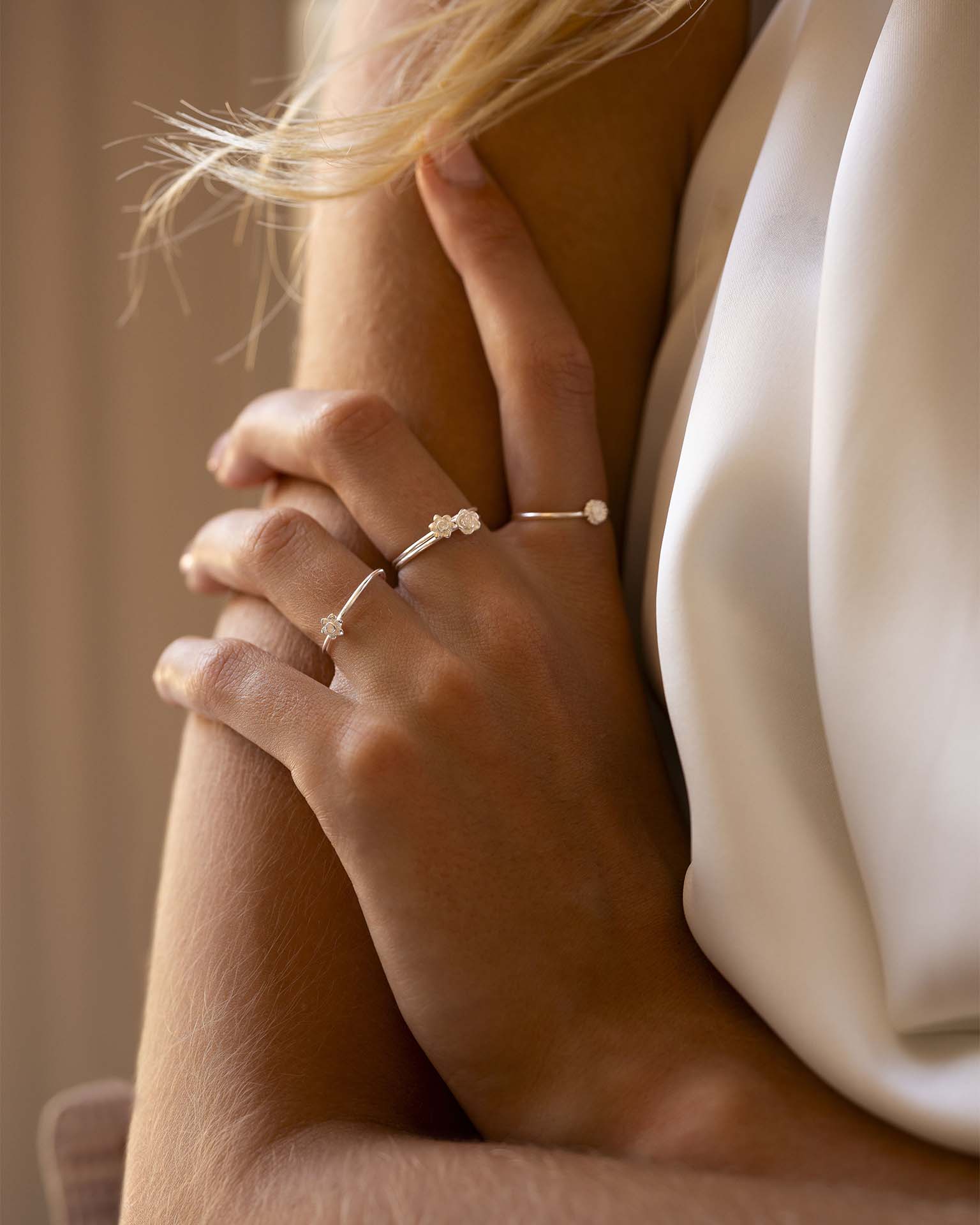Close-up of a person wearing multiple delicate rings on a soft background