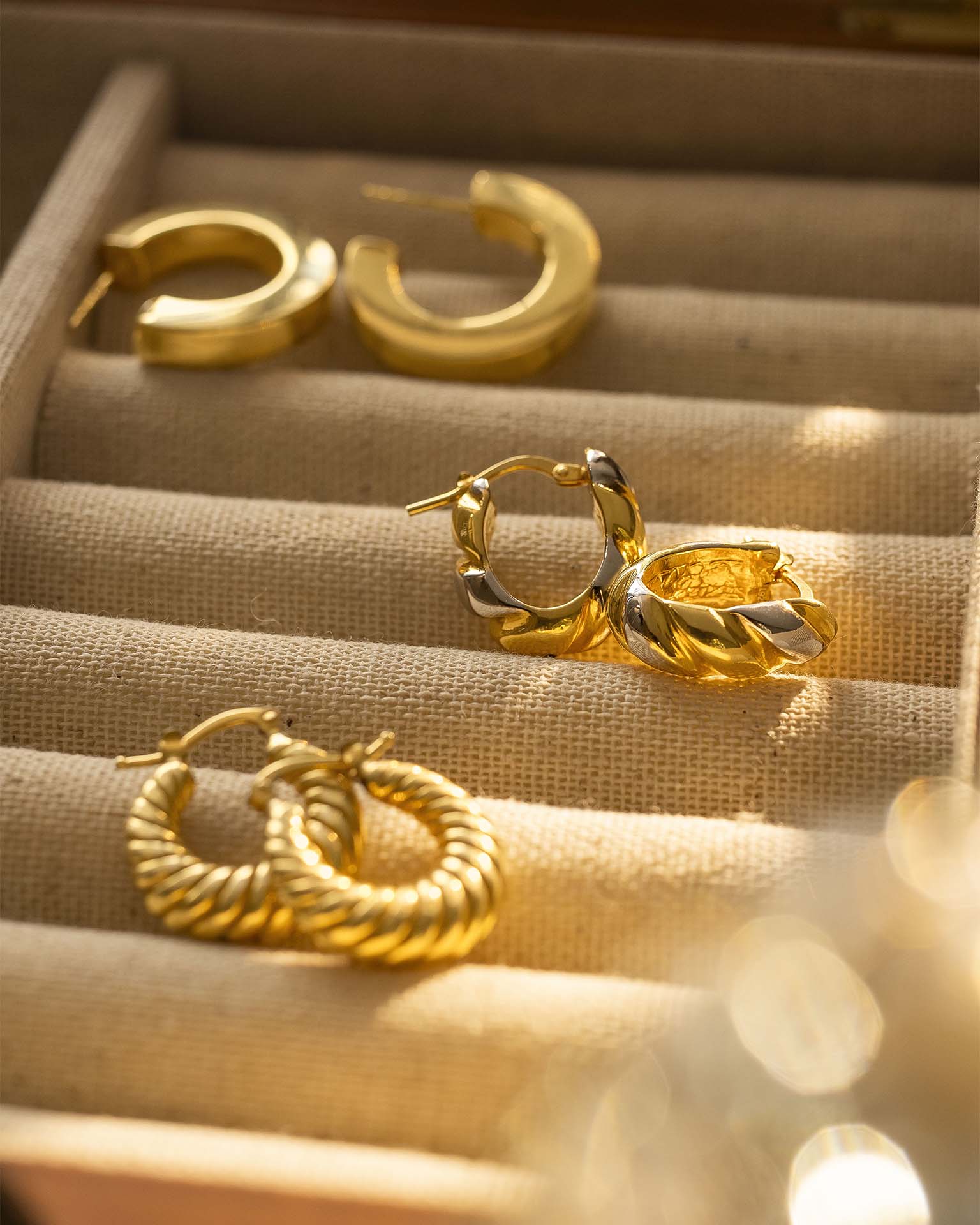 Gold hoop earrings on a soft fabric surface