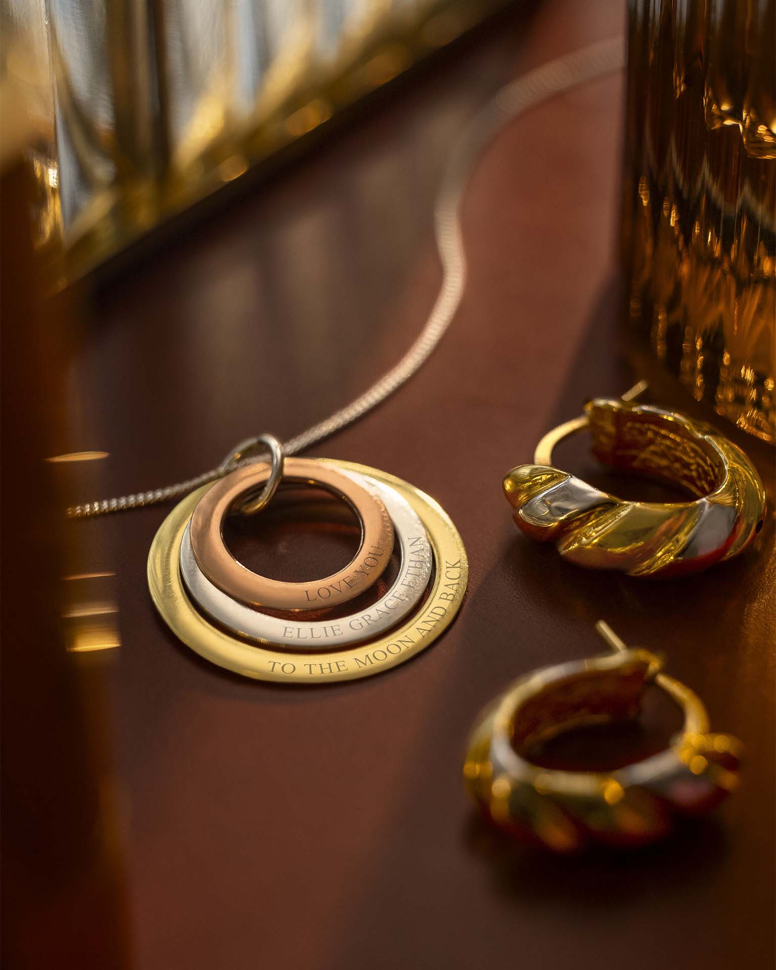 Gold necklace and earrings on a reflective surface