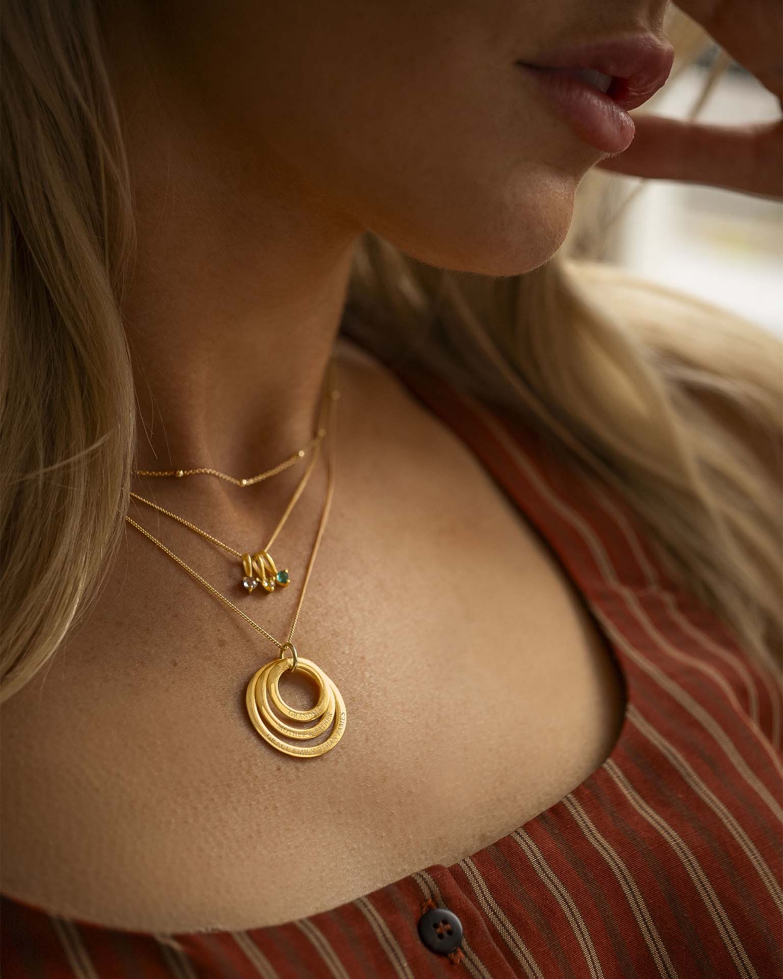 Close-up of a woman wearing gold necklaces with a blurred background
