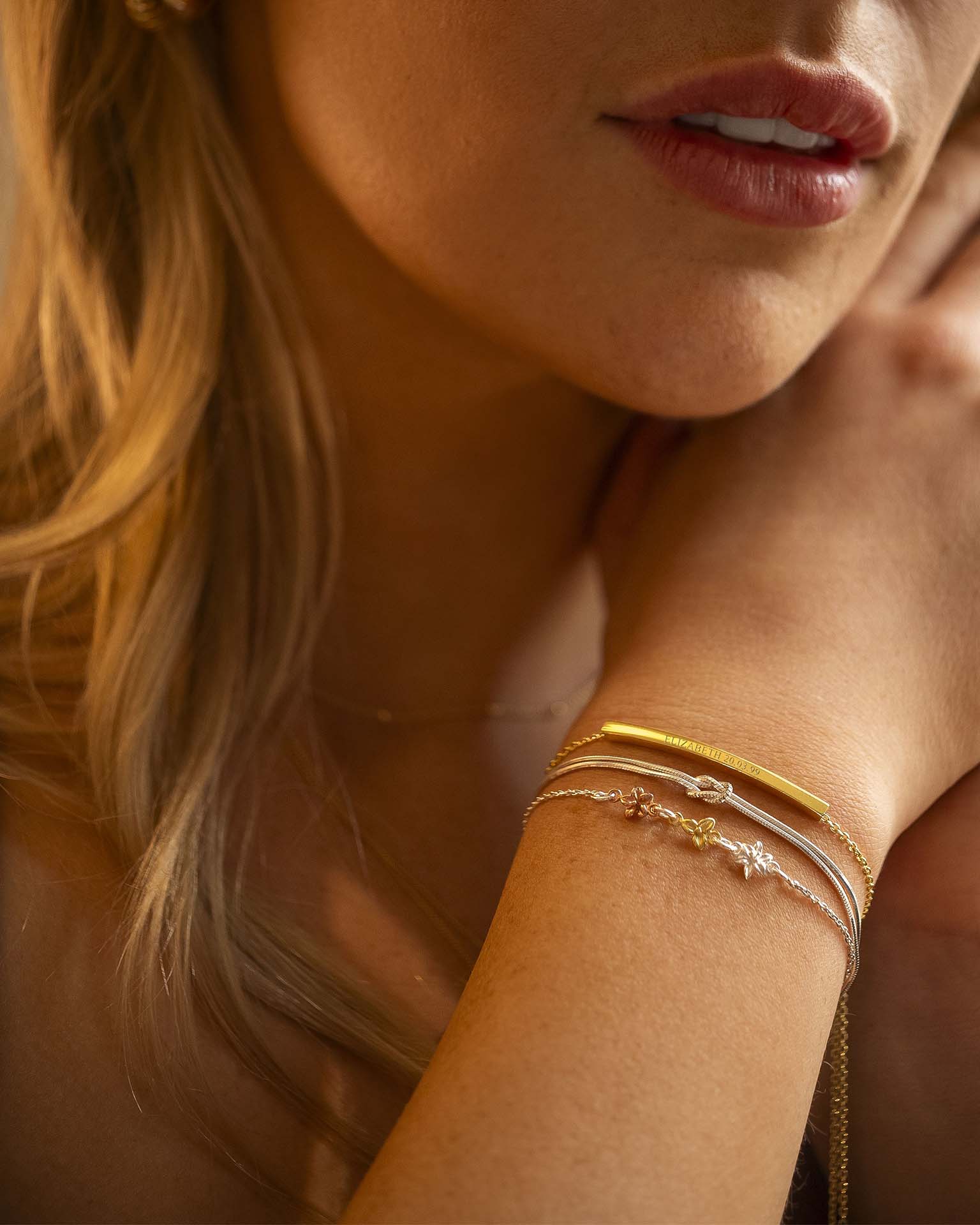 Close-up of a woman's arm with gold bracelets, focusing on jewelry.